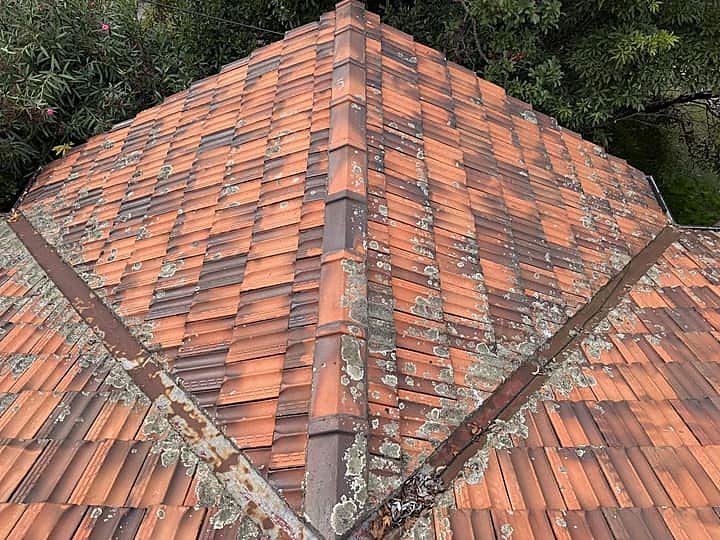 Terracotta hip roof with lichen growth, perished pointing and a rusted valley
