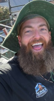 Ben Breheny of Y.M.I Roofing, smiling in his green wide-brim hat