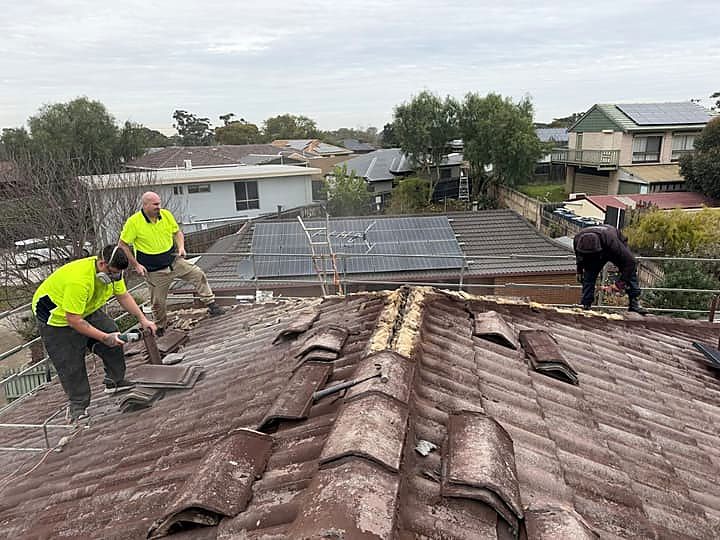 Three Y.M.I roofers working along a stripped ridge line on a Melbourne tile roof